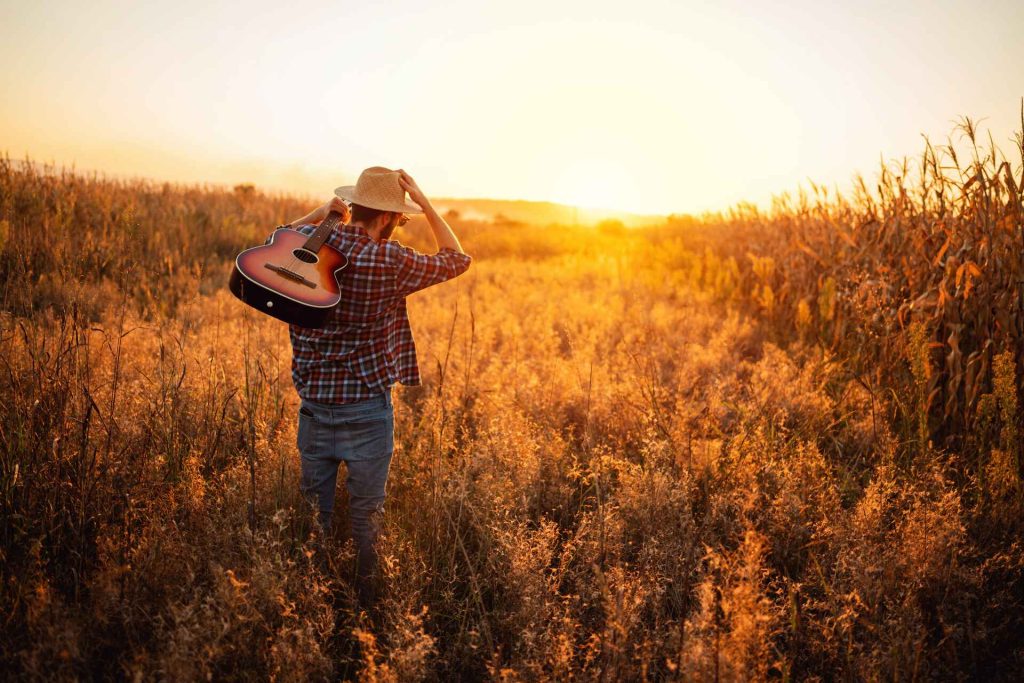 12 songs to make your crops grow taller - man in a field with a guitar