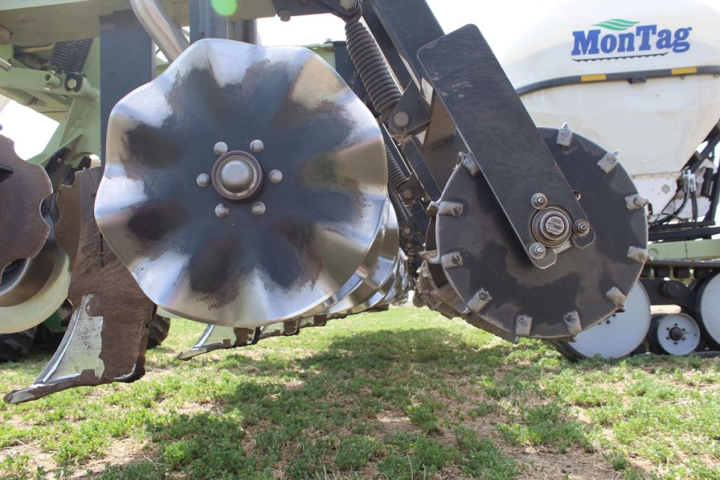 Farming vehicle with rotating blades preparing to cultivate the soil, highlighting a step in the cover cropping process for enhanced yield
